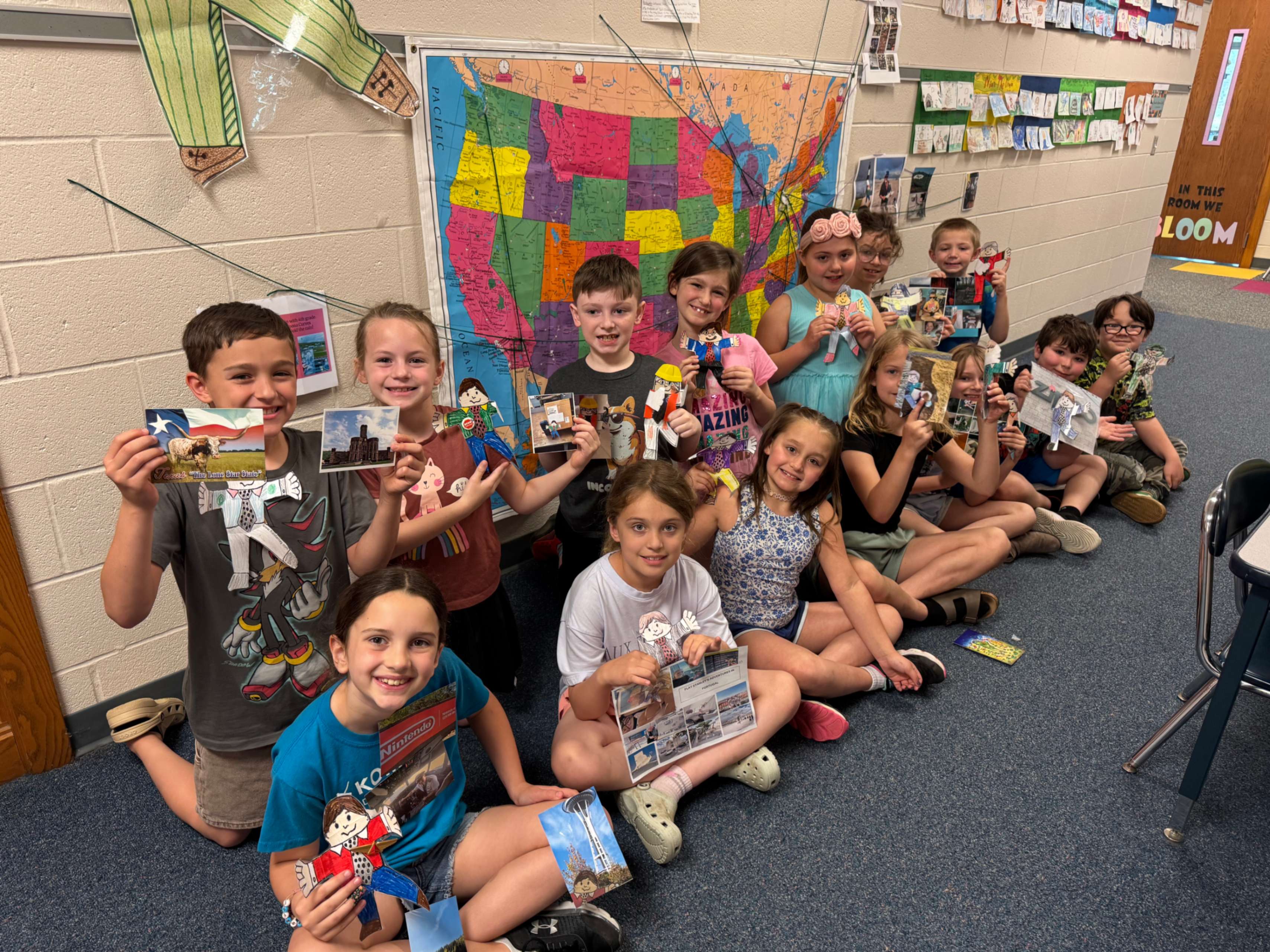 Several Pinecreek Elementary School students holding their Flat Stanleys and photos of where they have been.